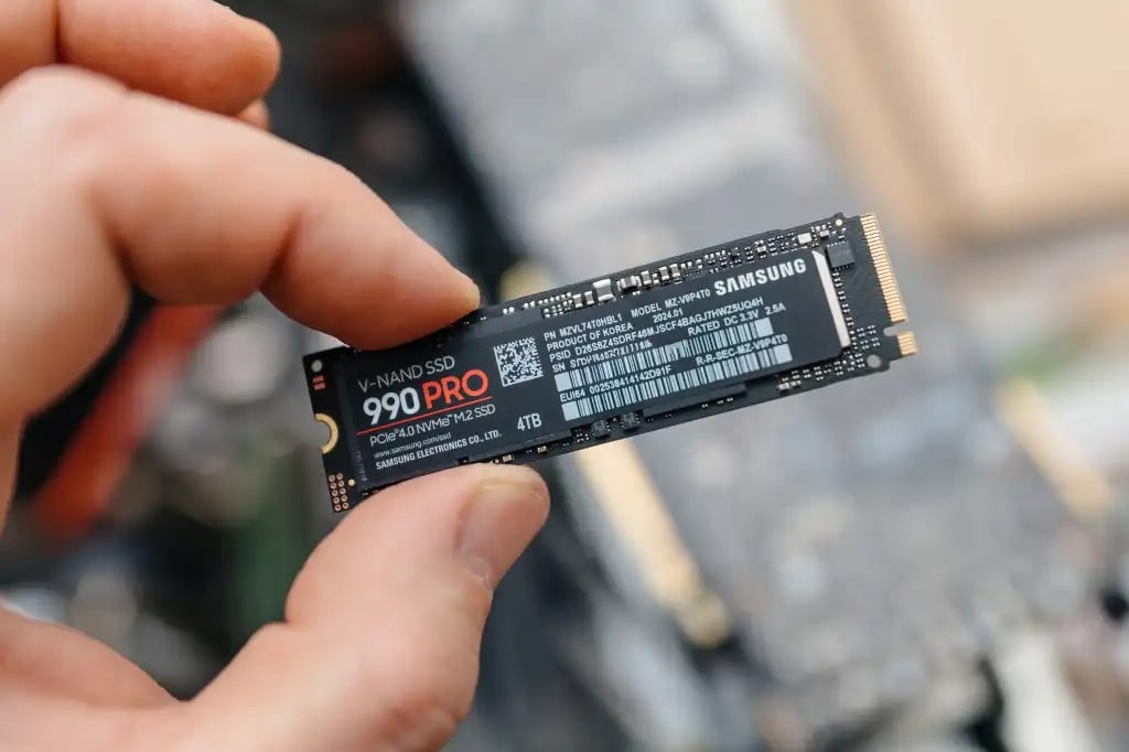 A person holds a 4TB Samsung 990 PRO SSD between two fingers