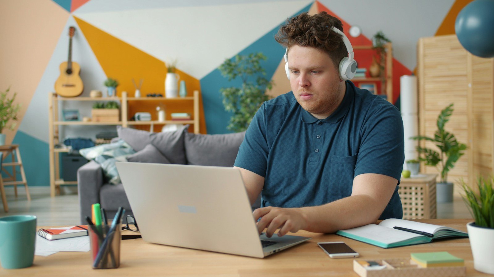 Person wearing headphones beside a laptop