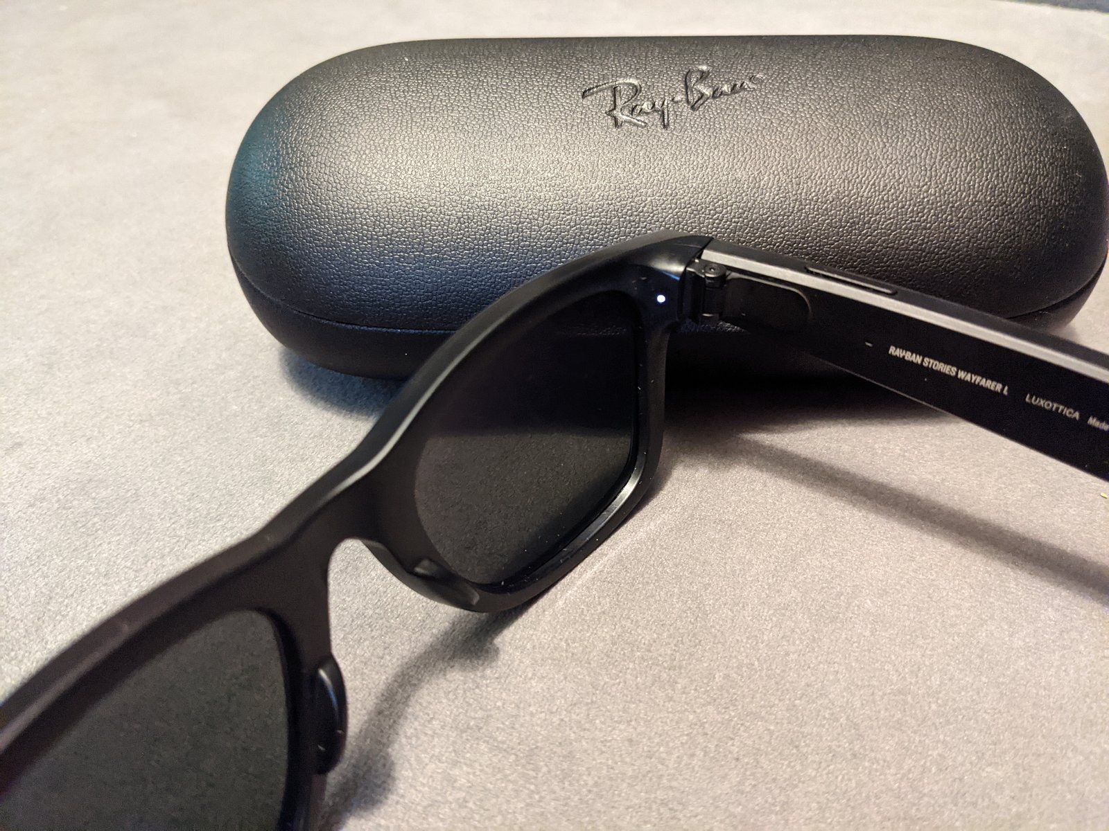 2021 Ray-Ban Stories glasses with the white front LED lit, next to their charging case
