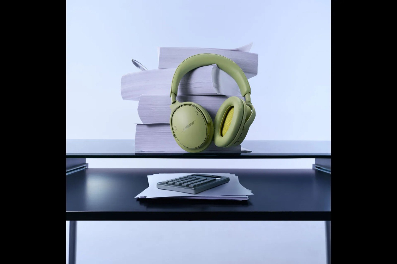 Auriculares Bose QuietComfort verdes expuestos en un estante junto a papeles