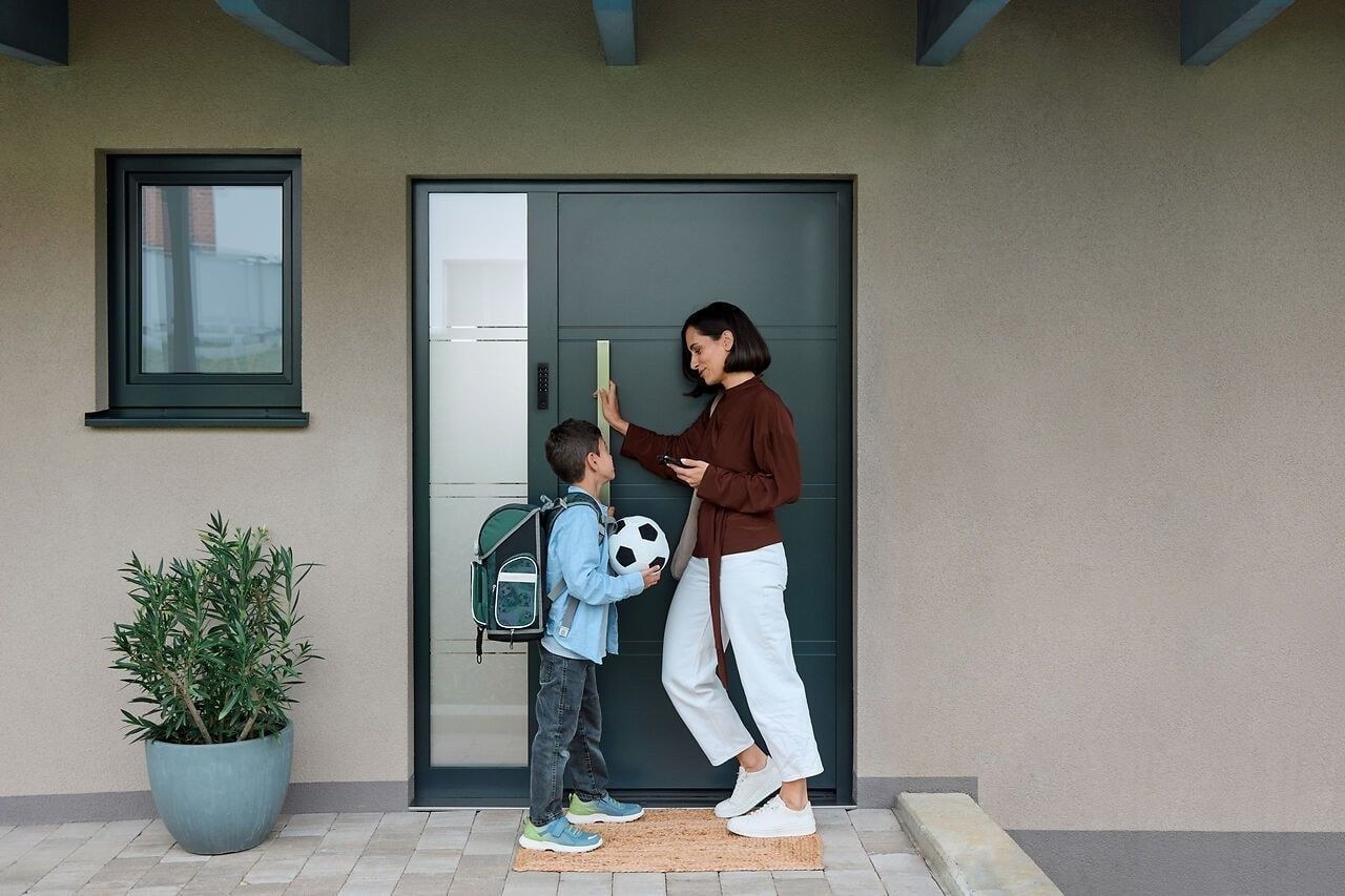 Una madre y su hijo delante de una puerta equipada con un teclado Nuki