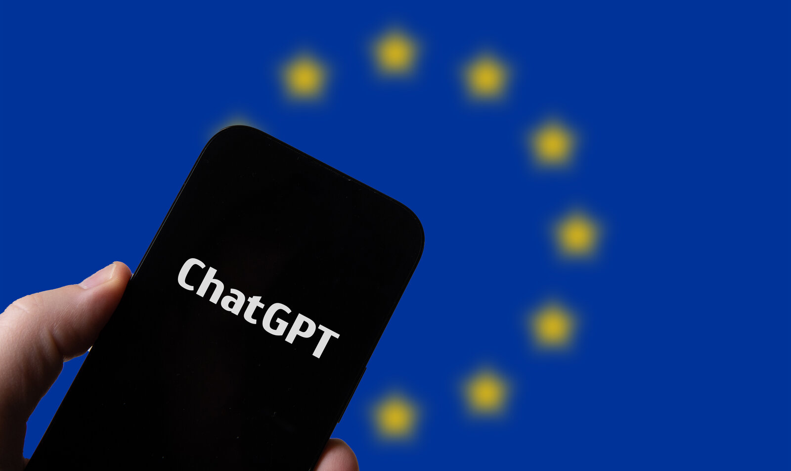 A hand holds a smartphone showing ChatGPT in front of a European Union flag