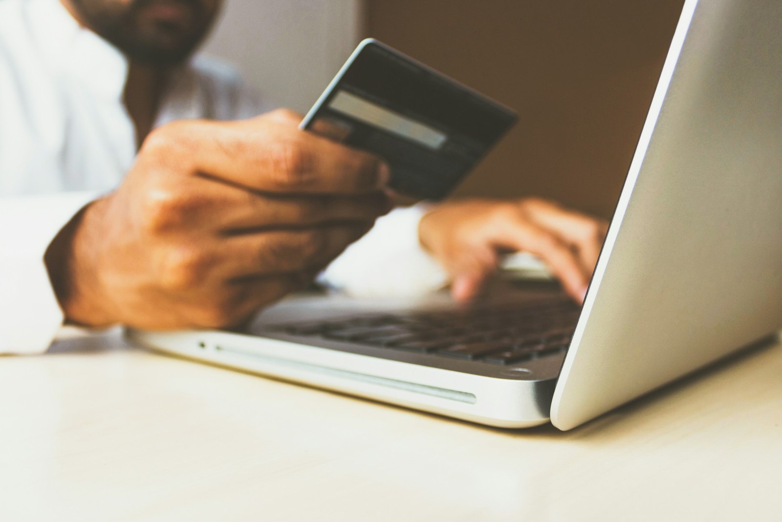 Una persona paga una compra online con tarjeta desde su portátil