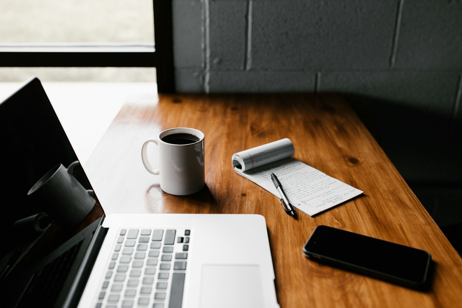 Laptop, notebook and coffee on a table, an illustrative document-work setting