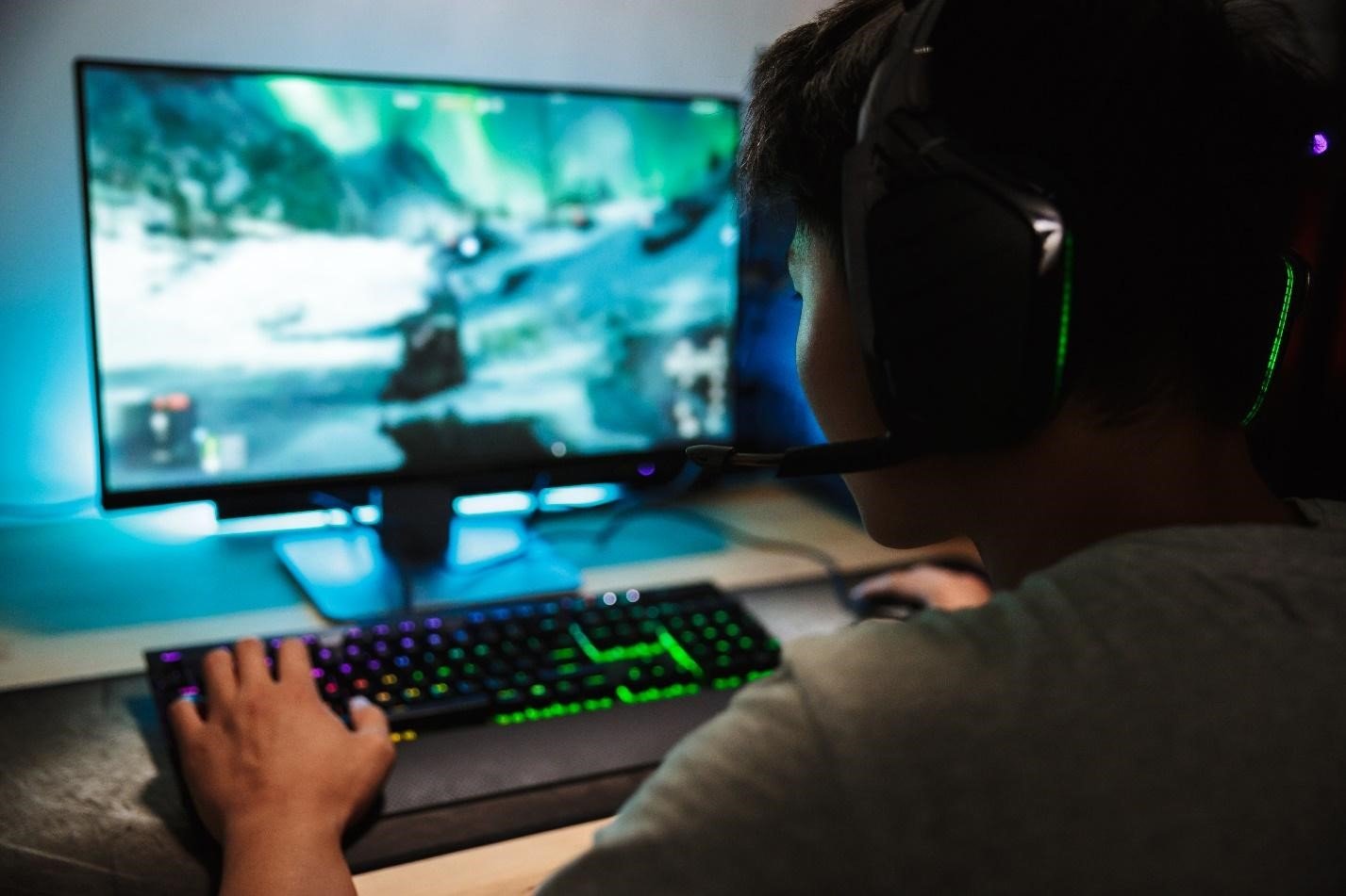 Un jugador prueba un videojuego en un PC con teclado iluminado y auriculares
