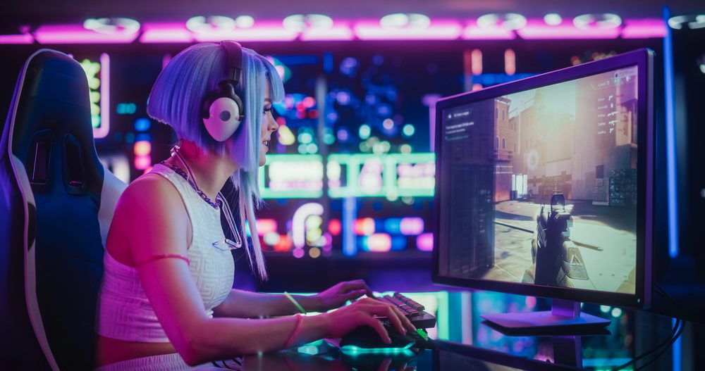 A gamer plays a shooter on a gaming PC surrounded by neon lights