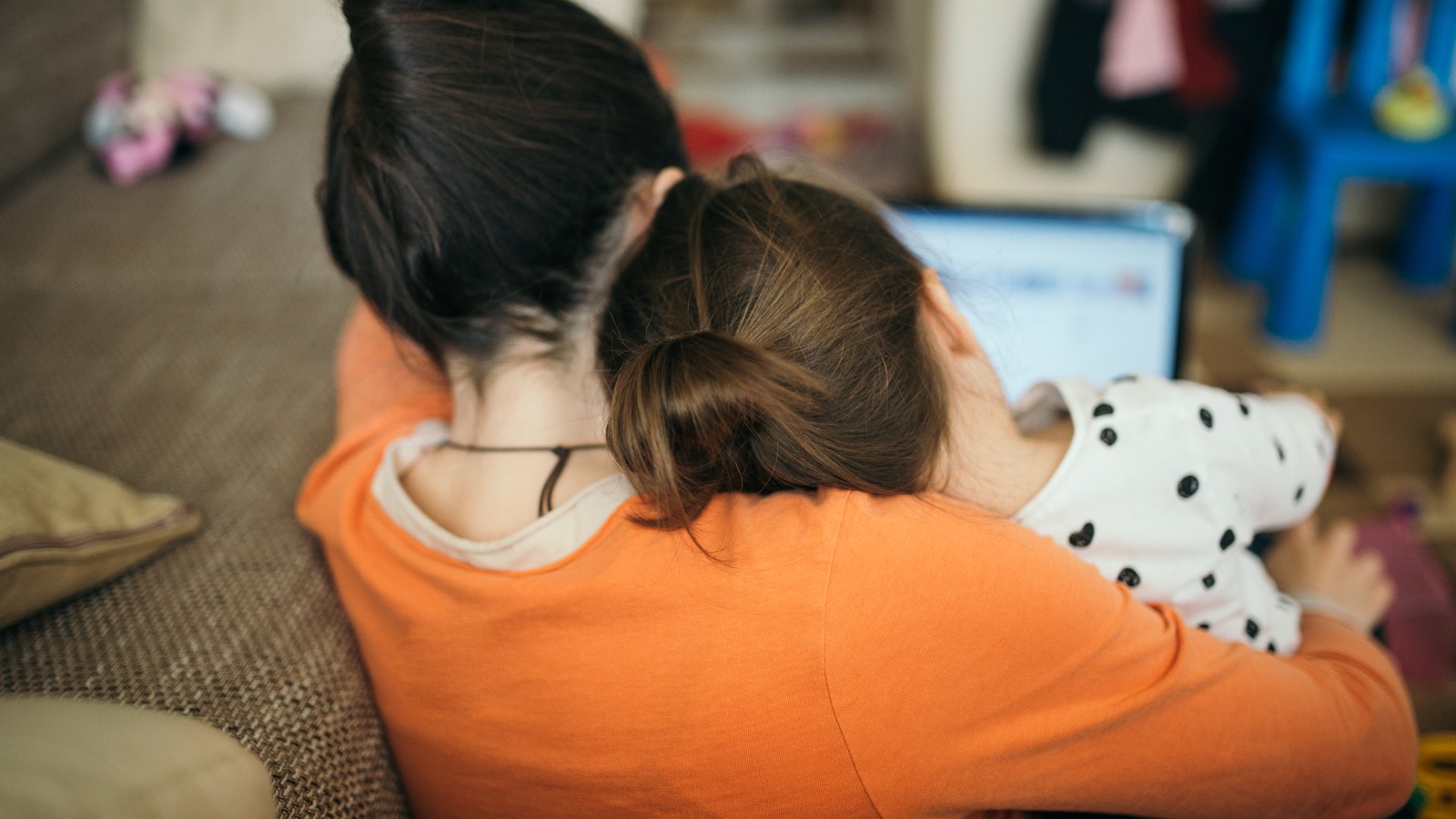 A mother and her daughter look at a laptop screen together