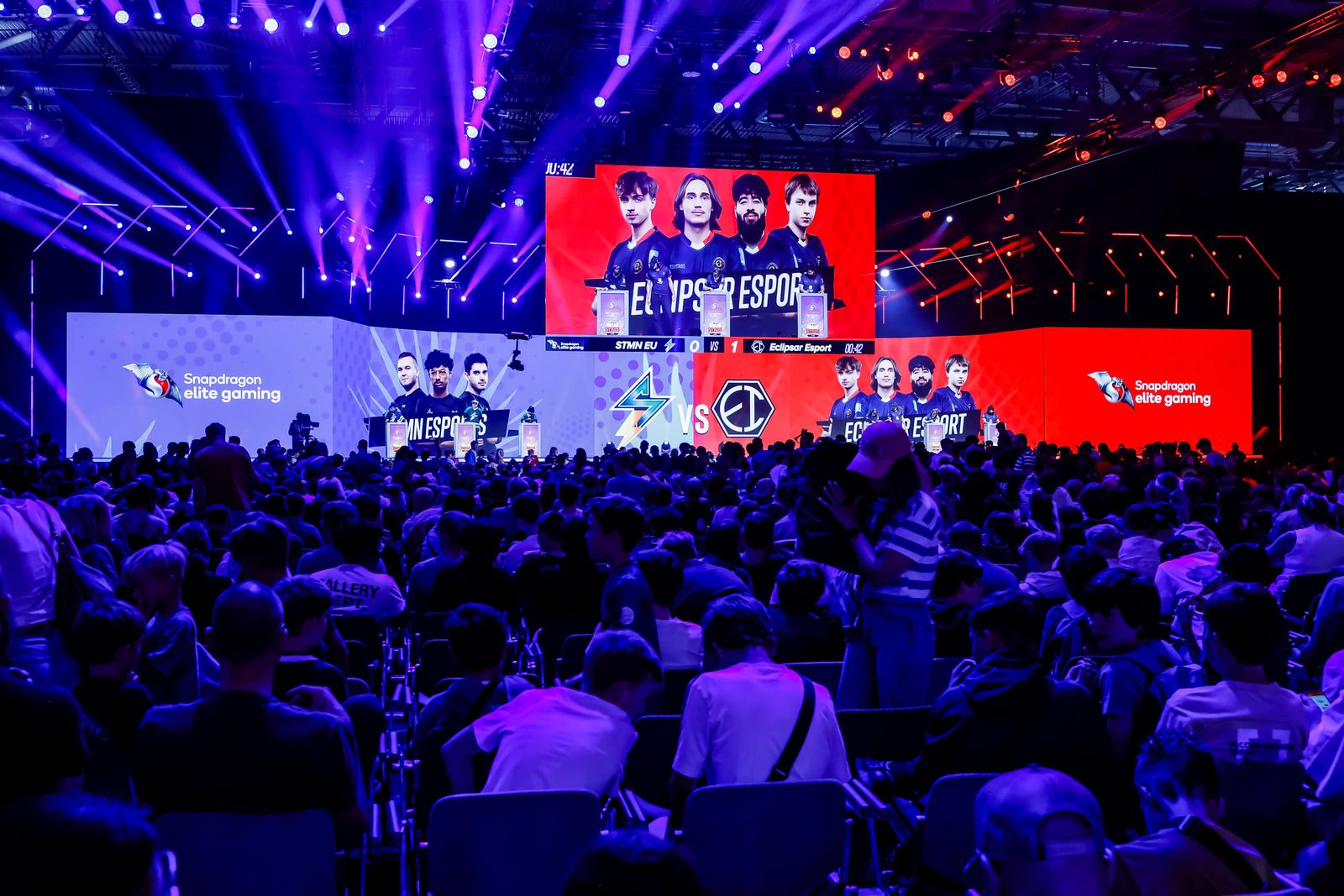 Thousands of attendees watch a competition on a brightly lit Gamescom stage
