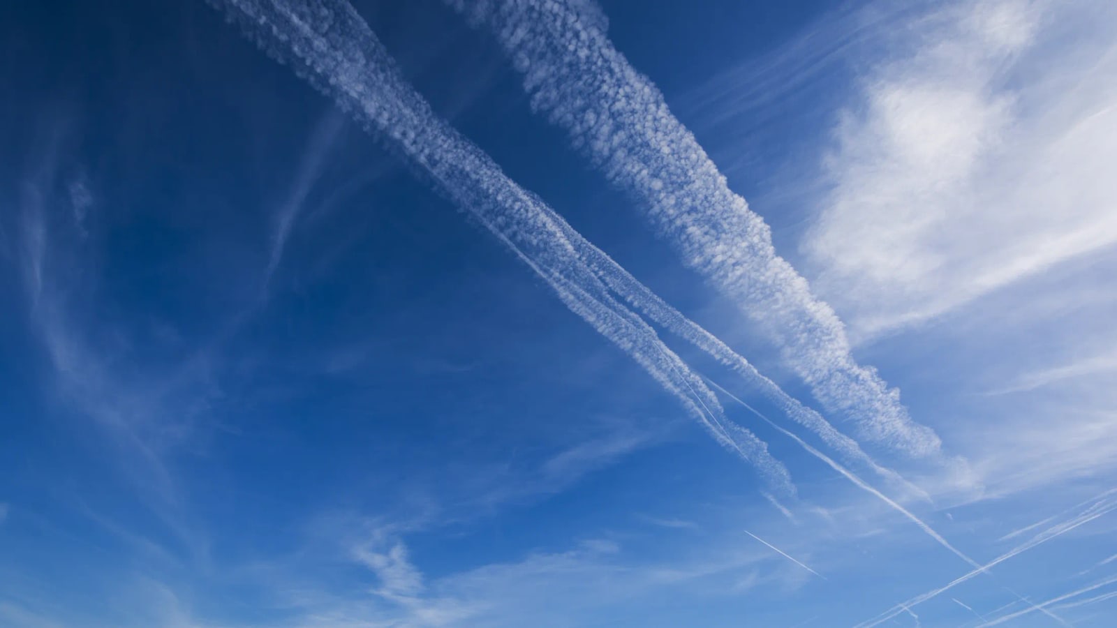 Several aircraft contrails crossing a blue sky