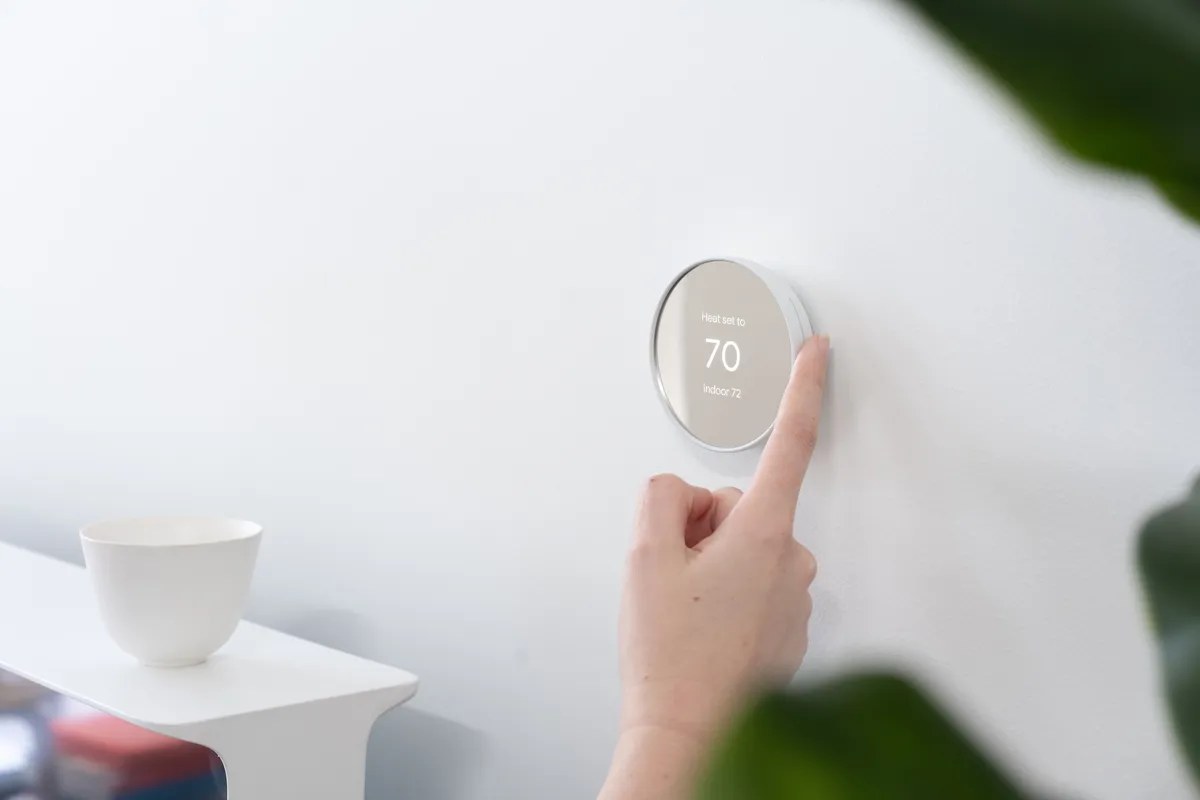 Una persona ajusta un termostato Nest, imagen ilustrativa de un hogar conectado