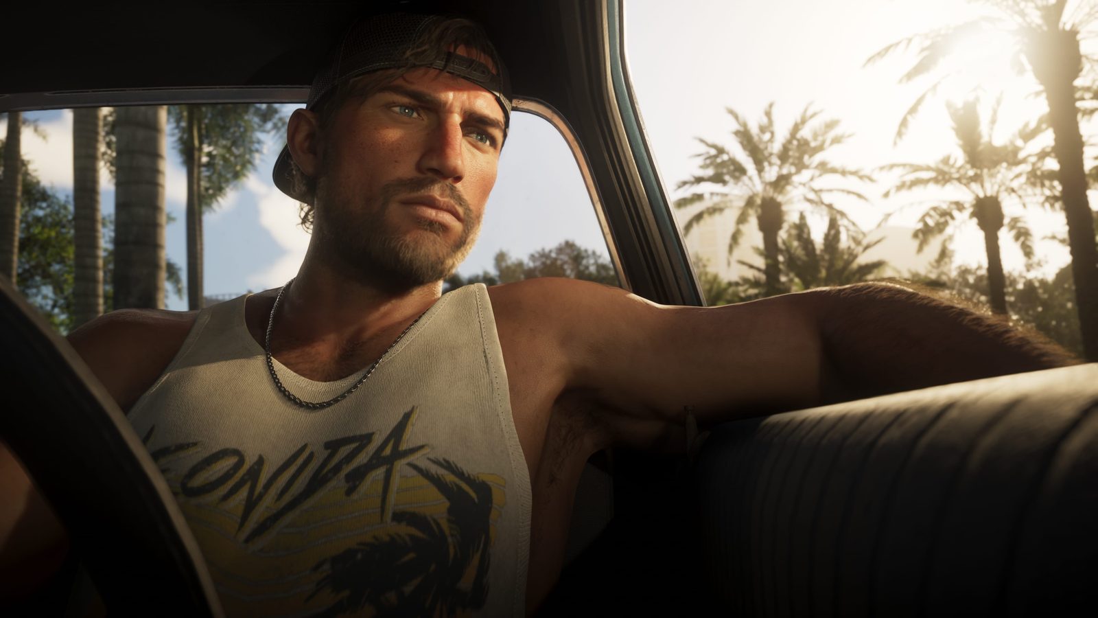 Jason, GTA 6's protagonist, at the wheel of a car in a Leonida tank top with palm trees behind him