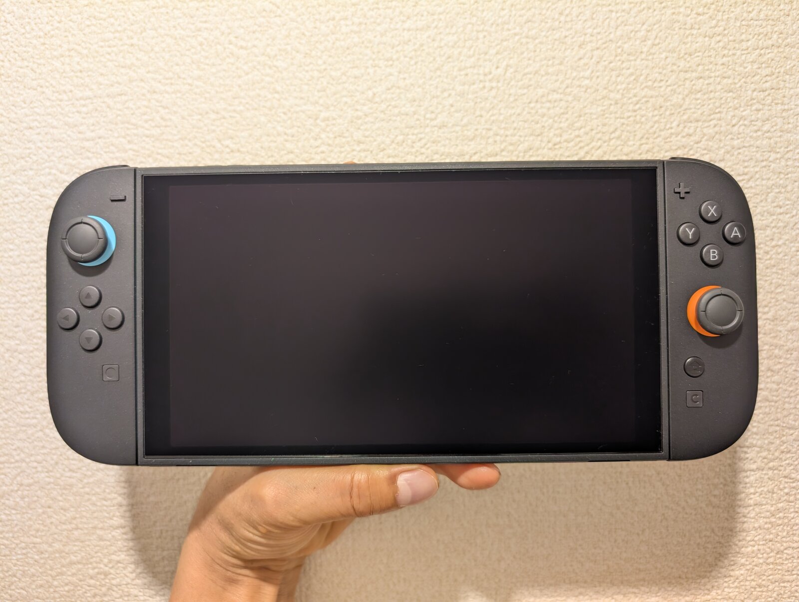 Una mano sostiene una Nintendo Switch 2 en modo portátil con la pantalla apagada