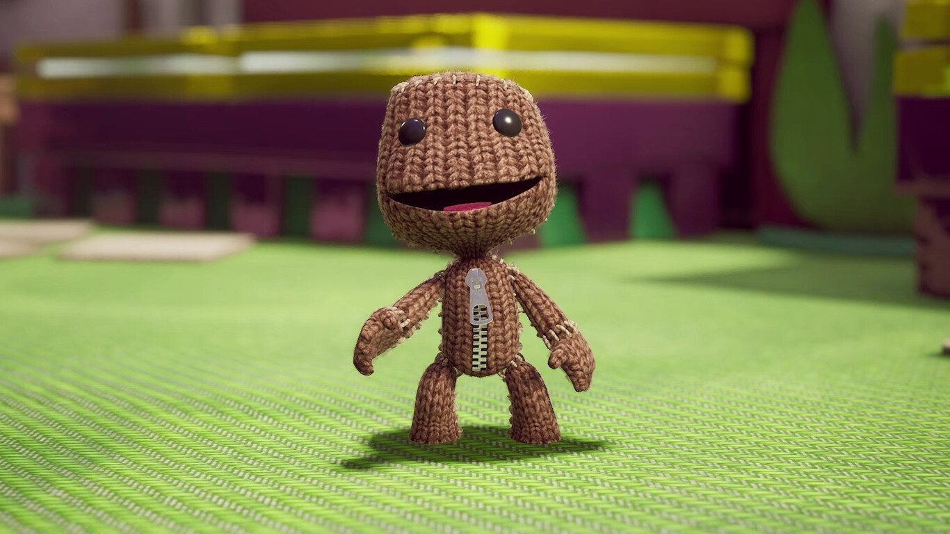 Sackboy smiles on a knitted-fabric stage in Sackboy: A Big Adventure