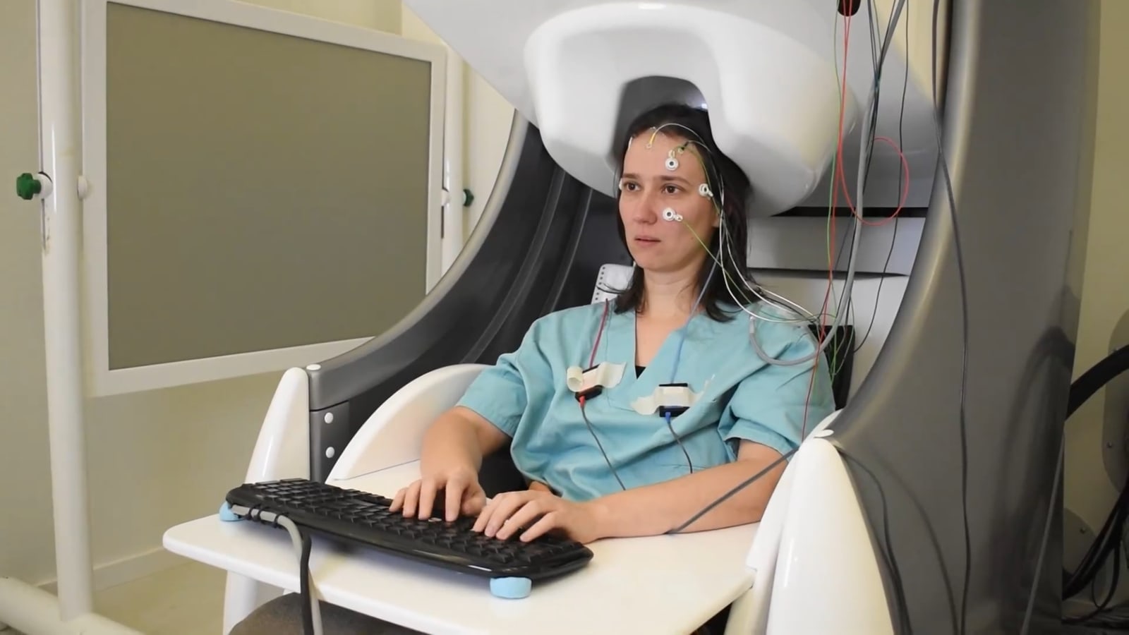 A volunteer types on a keyboard while a MEG scanner records her brain activity