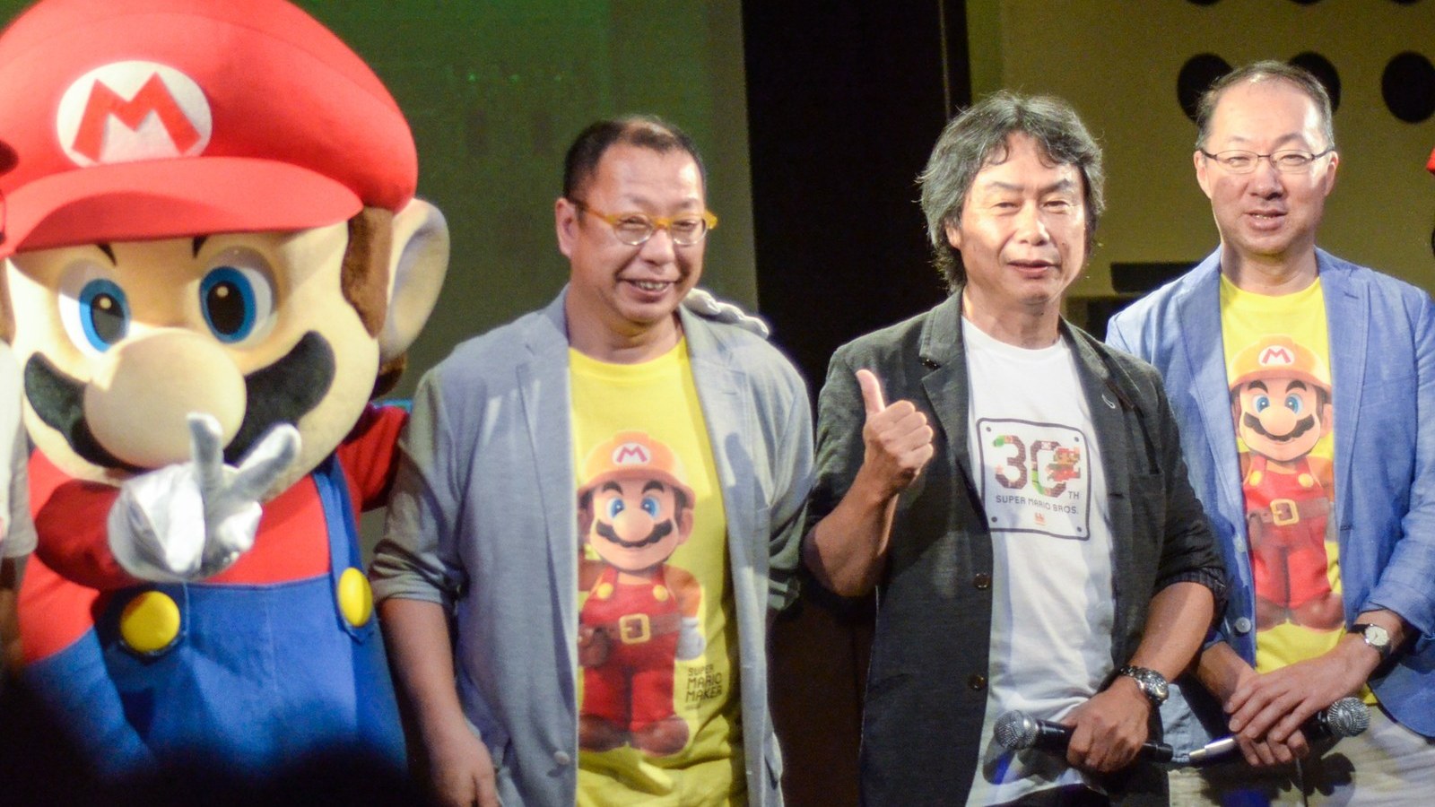 Shigeru Miyamoto gives a thumbs-up beside the Mario mascot, Takashi Tezuka and Koji Kondo at the Super Mario 30th anniversary event in Tokyo in 2015