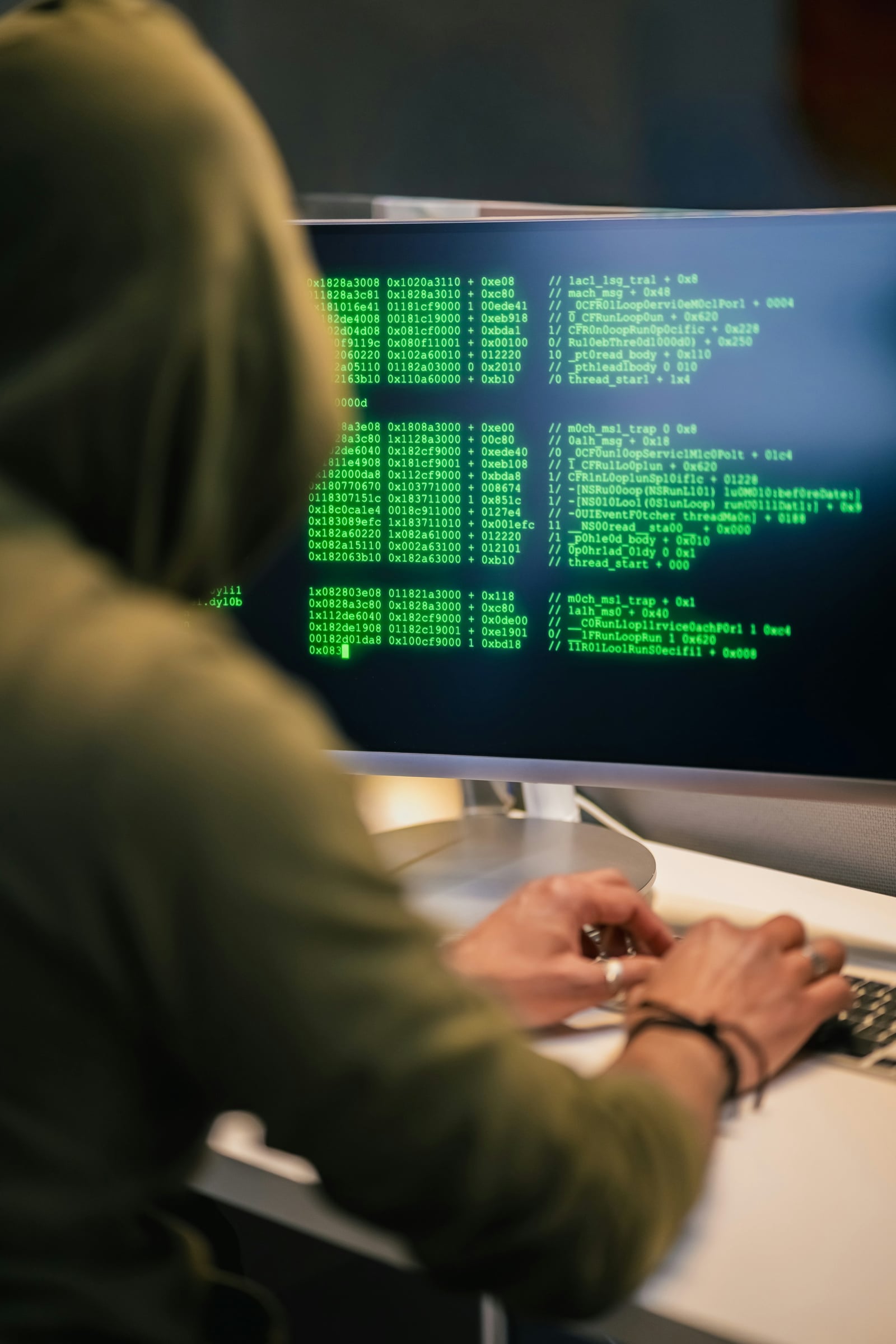 Persona frente a varias pantallas con código en una escena de ciberseguridad