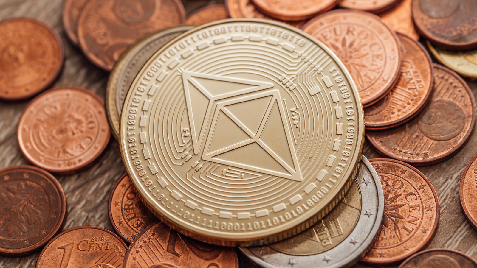 A novelty coin bearing the Ethereum logo resting on ordinary coins