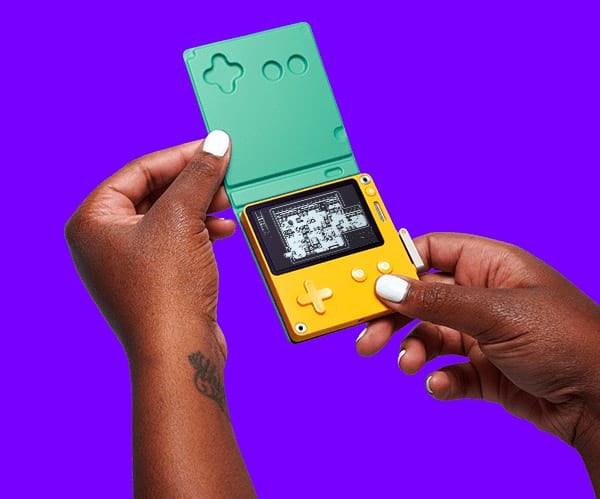 Hands holding a Playdate with a green cover against a purple background