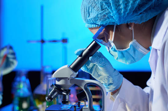 Researcher examines a sample through a microscope in a biotechnology laboratory