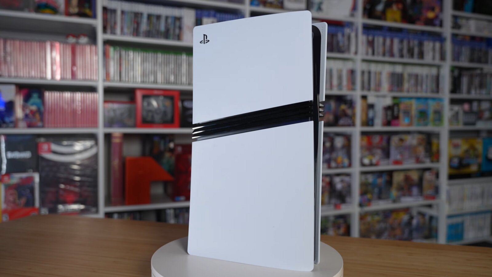 A PS5 Pro standing upright in front of shelves packed with video games
