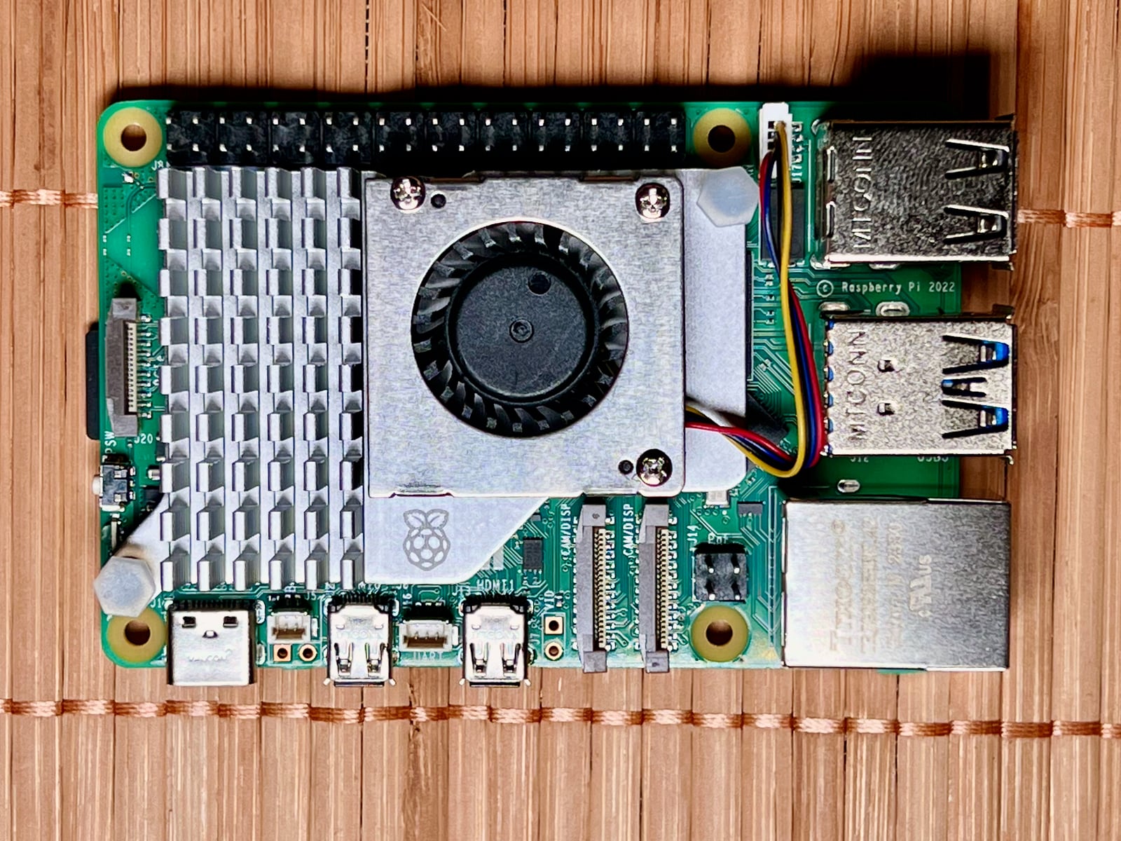 Raspberry Pi 5 on a wooden surface with a heatsink and fan installed
