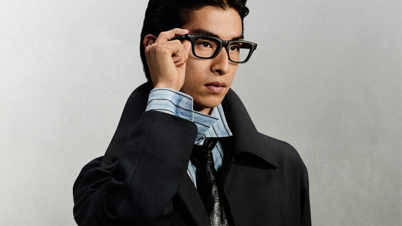 Hombre con unas Ray-Ban Meta de segunda generación, de montura rectangular negra, que se ajusta la patilla con la mano
