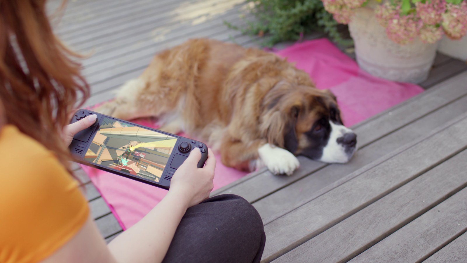 A person playing Steam Deck OLED beside a dog