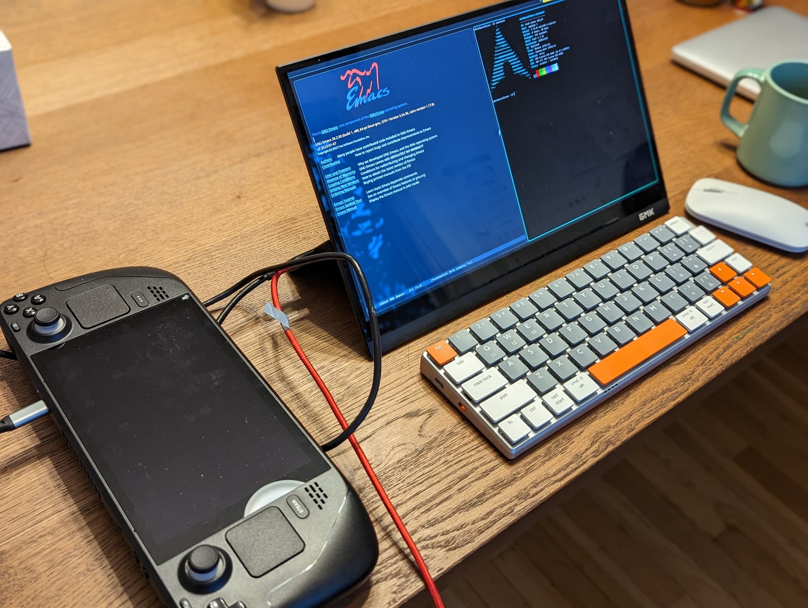 Steam Deck conectada a un monitor externo con escritorio Linux, teclado y ratón sobre una mesa
