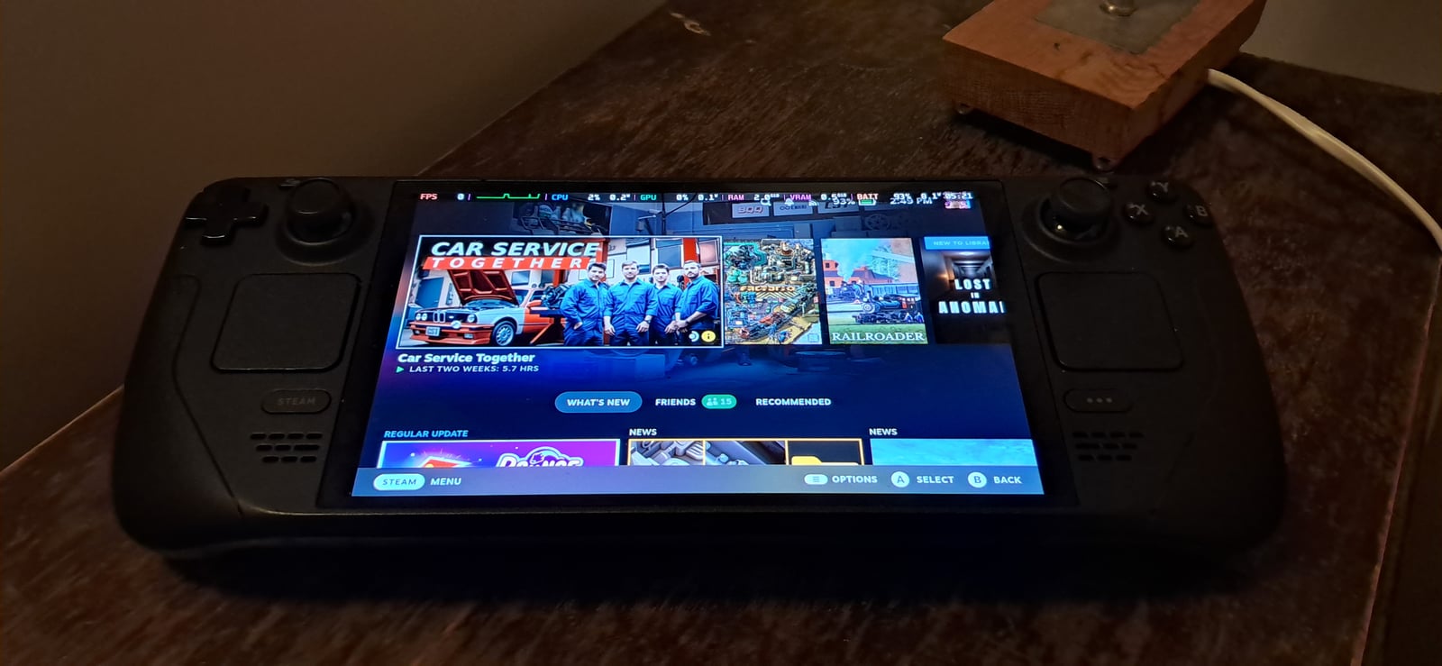 Steam Deck OLED sobre una mesa con la biblioteca de Steam y la superposición de rendimiento activada