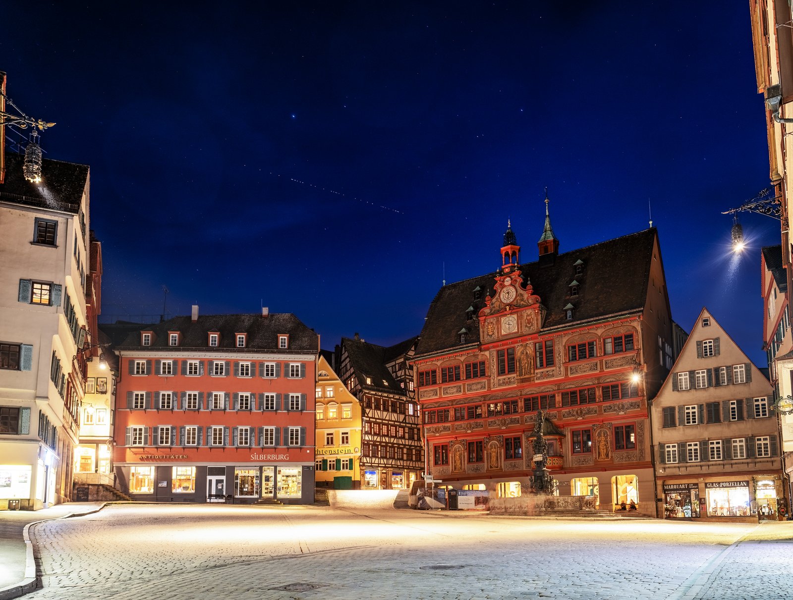 A train of Starlink satellites crosses the night sky as a dotted line above Tübingen town hall, Germany, in April 2020