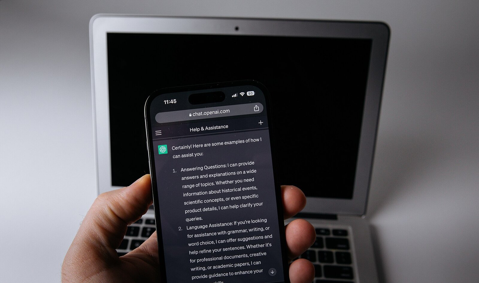 A phone with ChatGPT open held in front of a laptop